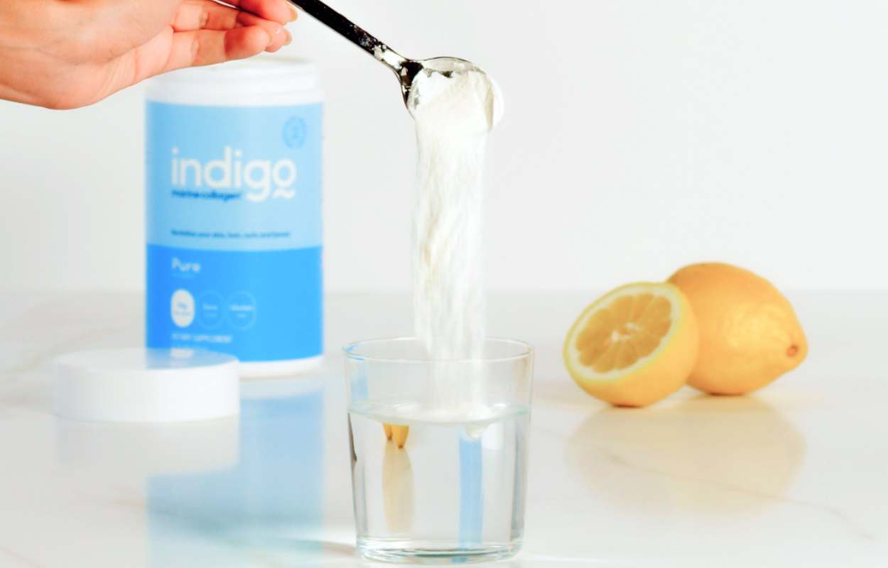 Image of Hand Putting Indigo Marine Collagen Peptides into a Glass of Water